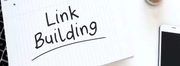 Notitieblok met de tekst ‘Link Building’, naast een smartphone en toetsenbord